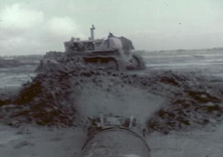 Screenshot from the corrected film of a pipe spraying water and a bulldozer moving dirt during the construction of the camp.