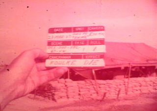 Screenshot from original film, William Foulke's clacker with his name on it. Film is red tinted.