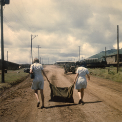 Jennifer Young and a fellow Donut Dolly carry a bag of activities at Camp Enari